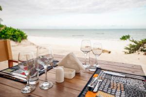 a wooden table with wine glasses on the beach at Mayai Ocean Resort in Bwejuu
