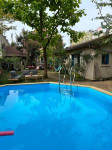 une piscine bleue avec deux bars en métal dans une cour dans l'établissement Le Clos du Moulin Dijon, avec son jardin calme et romantique, la campagne à la ville, à Dijon