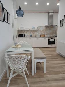 een witte keuken met een tafel en een stoel bij Gábriel Apartman 2 in Kőszeg