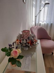een glazen tafel met een vaas met bloemen en een stoel bij Gábriel Apartman 2 in Kőszeg