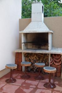 een buitenoven met drie krukken ervoor bij Apartmani Dina 1 in Posedarje