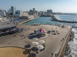 a beach with umbrellas and chairs and the water at Luxury 2BR Central TLV Apartment in Tel Aviv