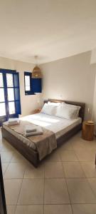 a large bed in a bedroom with blue windows at Oros Eros in Hydra