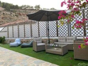 a patio with couches and an umbrella on the grass at Oros Eros in Hydra