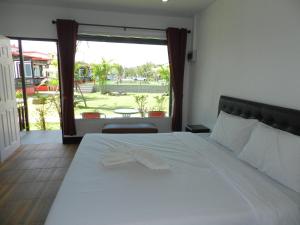 a bedroom with a white bed and a large window at Cape Go Resort in Chao Lao Beach