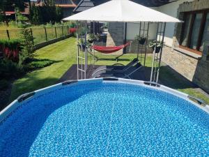 a swimming pool in a yard with an umbrella at Carlina Hotel & SPA in Białka Tatrzańska