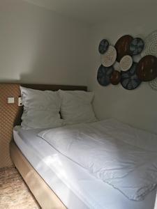 1 cama con sábanas blancas y placas en la pared en Akteon Hotel, en Stuttgart