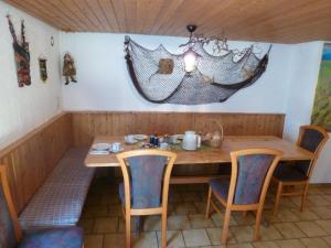 einem Holztisch mit Stühlen und einem Regenschirm an der Wand in der Unterkunft Privatzimmer Rethaber in Ringsheim