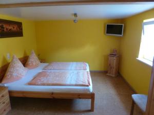 ein Schlafzimmer mit einem Bett in einer gelben Wand in der Unterkunft Privatzimmer Rethaber in Ringsheim