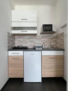 uma cozinha com um frigorífico branco e um micro-ondas em Lux apartments em Orosháza