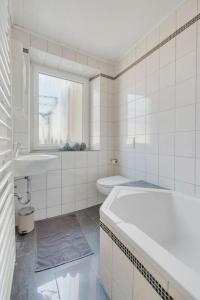 a white bathroom with a tub and a sink at Tiny apartment with spacious terrace on the Rhine in Neuwied