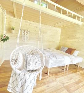 eine Schaukel in einem Zimmer mit einem Bett und einem Stuhl in der Unterkunft イリワ -stay&coffee iriwa- in Ishigaki-jima