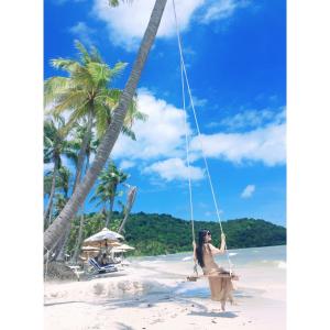 a woman on a swing on the beach at Palm Bay Resort Phu Quoc in Phú Quốc