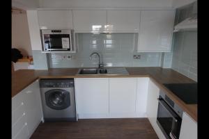 a kitchen with a sink and a washing machine at City Riverview Apartment with Parking in London