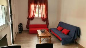 ein Wohnzimmer mit einem roten und blauen Sofa und einem Tisch in der Unterkunft Angela's Luxury Apartments in Kamena Vourla