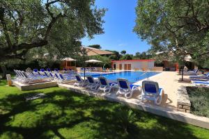 um grupo de cadeiras sentadas ao lado de uma piscina em Mediterranean Village San Antonio em Biograd na Moru