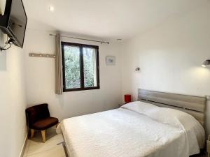 een slaapkamer met een bed, een raam en een stoel bij La Petite Bergerie in Plan-de-la-Tour
