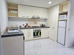 a kitchen with white cabinets and a white refrigerator at Light & Airy Heart of Central Kelburn! in Wellington