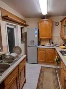 eine Küche mit Holzschränken und einem weißen Kühlschrank in der Unterkunft Luxury super double bedroom London Seven Kings Train station in Seven Kings
