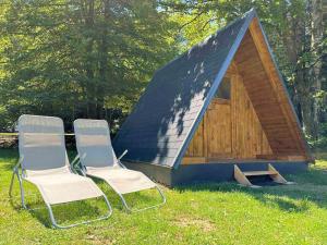 2 chaises assises devant une petite cabine dans l'établissement ECO River Camp, à Radovljica