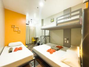 two beds in a room with orange walls at Puerto Princesa Airport Side Hostel in Puerto Princesa City