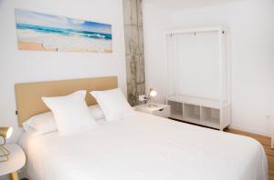 Un dormitorio blanco con una cama blanca y una ventana en P1 O Grove centro puerto en O Grove