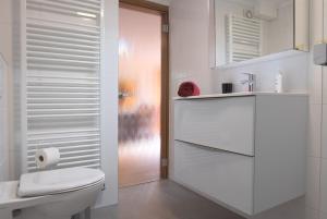 a white bathroom with a toilet and a sink at Ferienwohnung An den Linden in Kelmis