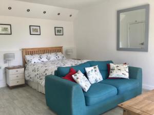 a blue couch in a bedroom with a bed at Wadebridge Whitecross studio 1 in Wadebridge