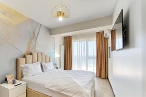 ein Schlafzimmer mit einem weißen Bett und einem Fenster in der Unterkunft Smarald Sea View Apartment in Infinity Beach Resort - parking in Mamaia