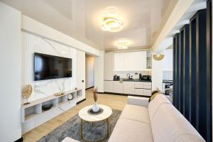 a living room with a couch and a tv at Smarald Sea View Apartment in Infinity Beach Resort - parking in Mamaia