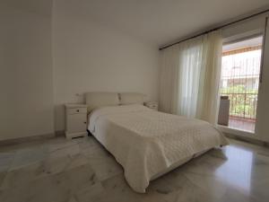 a white bedroom with a bed and a window at Room near the sea in Marbella