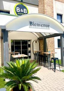 um restaurante com mesas e cadeiras em frente a um edifício em B&B HOTEL Aubagne Gémenos em Gémenos