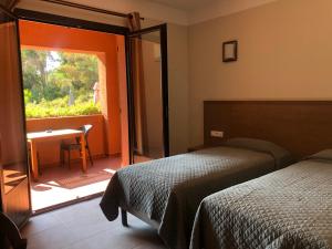 ポルトにあるHotel Corsica - Porto Corseのベッドルーム1室(ベッド1台、テーブル、窓付)