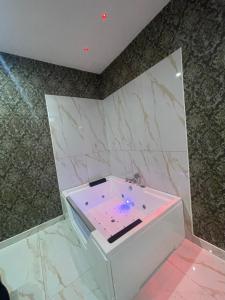 Life Hotel في كازالنووفو دي نابولي: حوض استحمام أبيض في غرفة مع جدران من الرخام