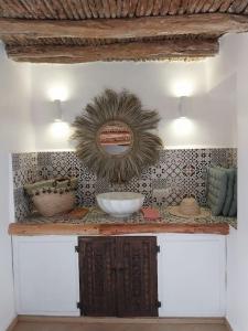 ein Regal mit einem Spiegel und Schalen an einer Wand in der Unterkunft Riad plain pied 2 chambres jardin terrasse & bassin in Tamraght Ouzdar