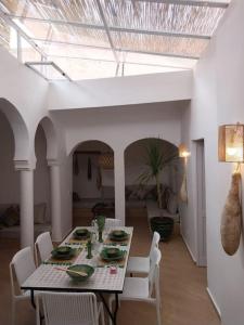 ein Esszimmer mit einem Tisch und weißen Stühlen in der Unterkunft Riad plain pied 2 chambres jardin terrasse & bassin in Tamraght Ouzdar