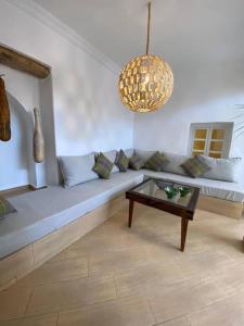 ein Wohnzimmer mit einem Sofa und einem Tisch in der Unterkunft Riad plain pied 2 chambres jardin terrasse & bassin in Tamraght Ouzdar