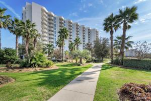 a walkway in front of a building with palm trees at Palms Resort #2416 Full 2 Bedroom in Destin
