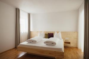 a bedroom with a bed with white sheets and pillows at Untermairhof Appartment Residence in Selva dei Molini