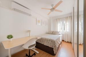een witte slaapkamer met een bureau, een bed en een tafel bij Living Caja Mágica in Madrid