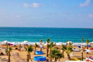 a beach with palm trees and the ocean at Paradise Inn Beach Resort in Alexandria