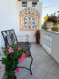 Vena的住宿－B&B Via del Sole，坐在门廊上,种着鲜花的黑色长凳