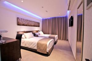 2 łóżka w pokoju hotelowym z fioletowymi światłami w obiekcie Achilleos City Hotel w Larnace