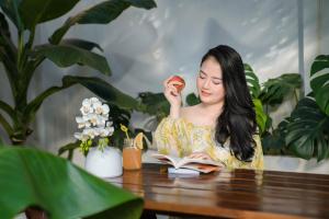 a woman sitting at a table reading a book and eating an apple at Tam Coc Moment Homestay in Ninh Binh +24 photos