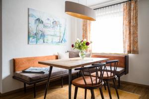 uma mesa de jantar e cadeiras com um vaso de flores em Der Ballhaushof em Prutz