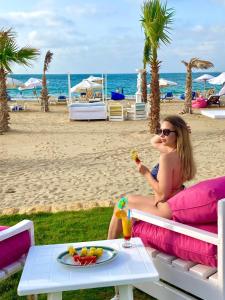 una mujer sentada en un banco en la playa comiendo comida en Paradise Inn Beach Resort, en Alejandría