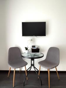 Duas cadeiras e uma mesa com uma televisão na parede em Lux apartments em Orosháza
