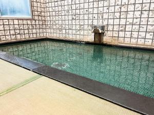a swimming pool with a fountain in a building at Asama Onsen FAN! MATSUMOTO in Matsumoto