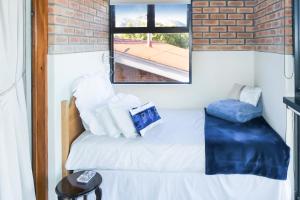 a bedroom with a white bed with a brick wall at Shalom Self Catering in Kleinmond