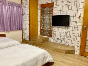 een slaapkamer met een bed en een tv aan de muur bij Fu Hwa Homestay in Nangan